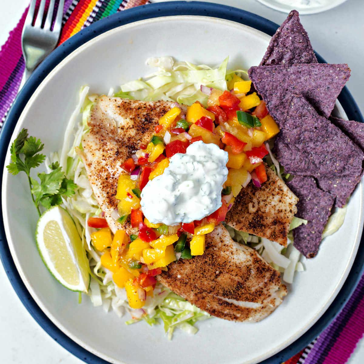 bowls of mango salsa with water chestnuts served with tortilla chips and grilled fish