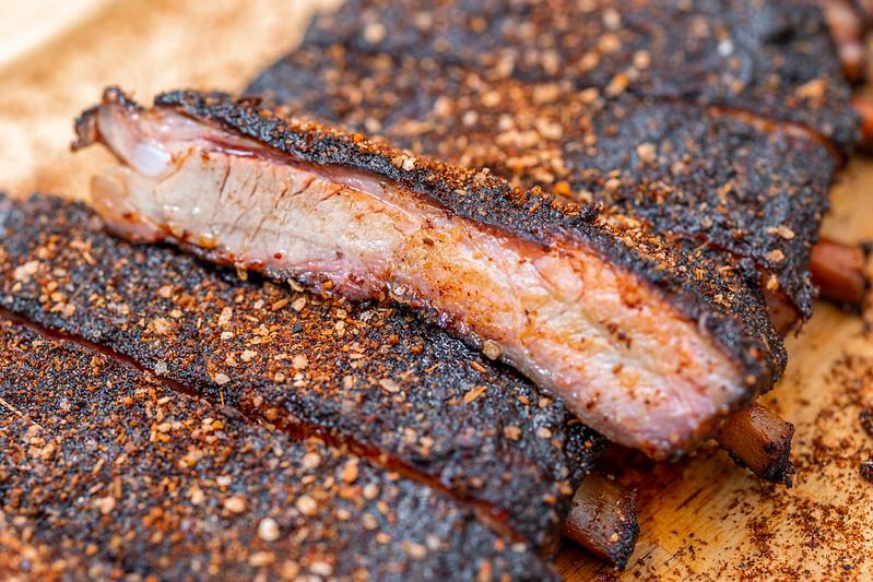 ancho chili powder being sprinkled on ribs