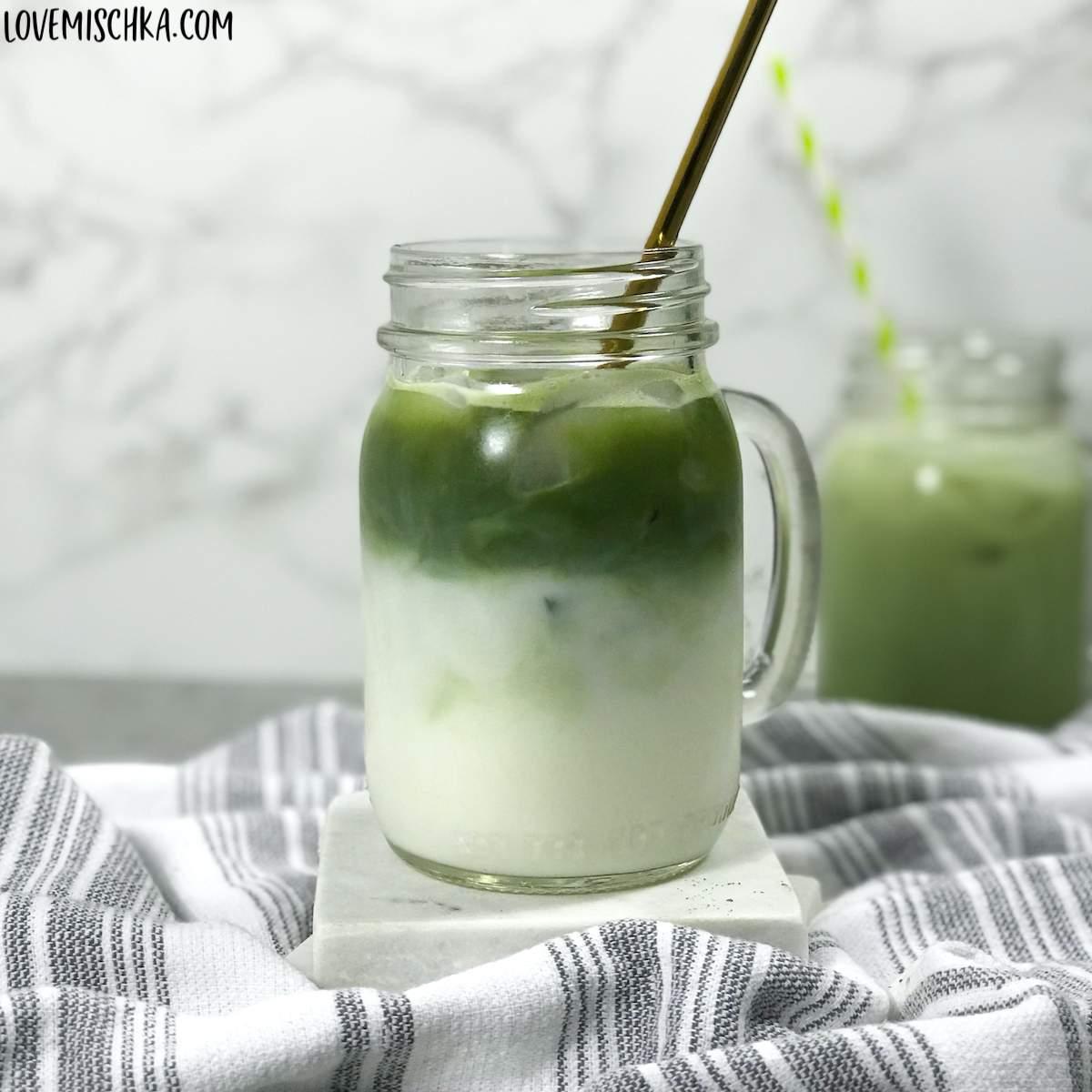 matcha latte being poured into a clear glass, showing the layers of green and white
