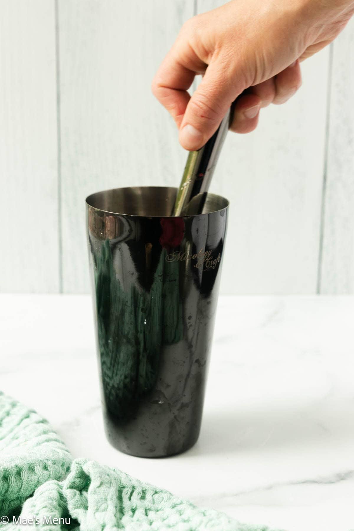 hands muddling mint and watermelon in a glass