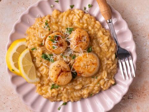 Yuzu and scallop risotto plated beautifully with citrus garnish
