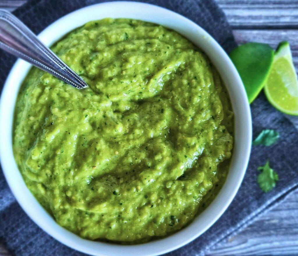 a bowl of freshly made avocado salsa with a spoon