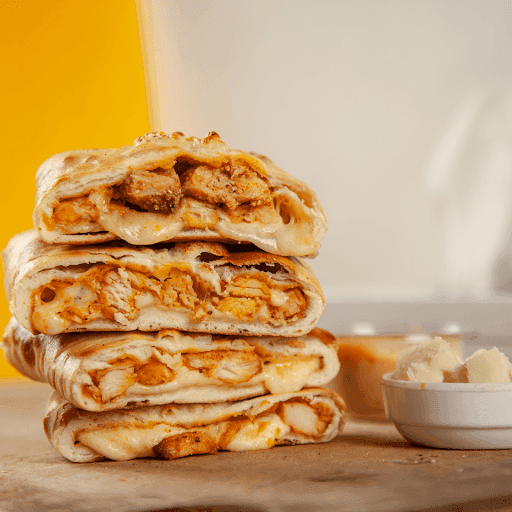 A batch of golden brown chicken parmesan calzones fresh out of the oven, garnished with fresh basil