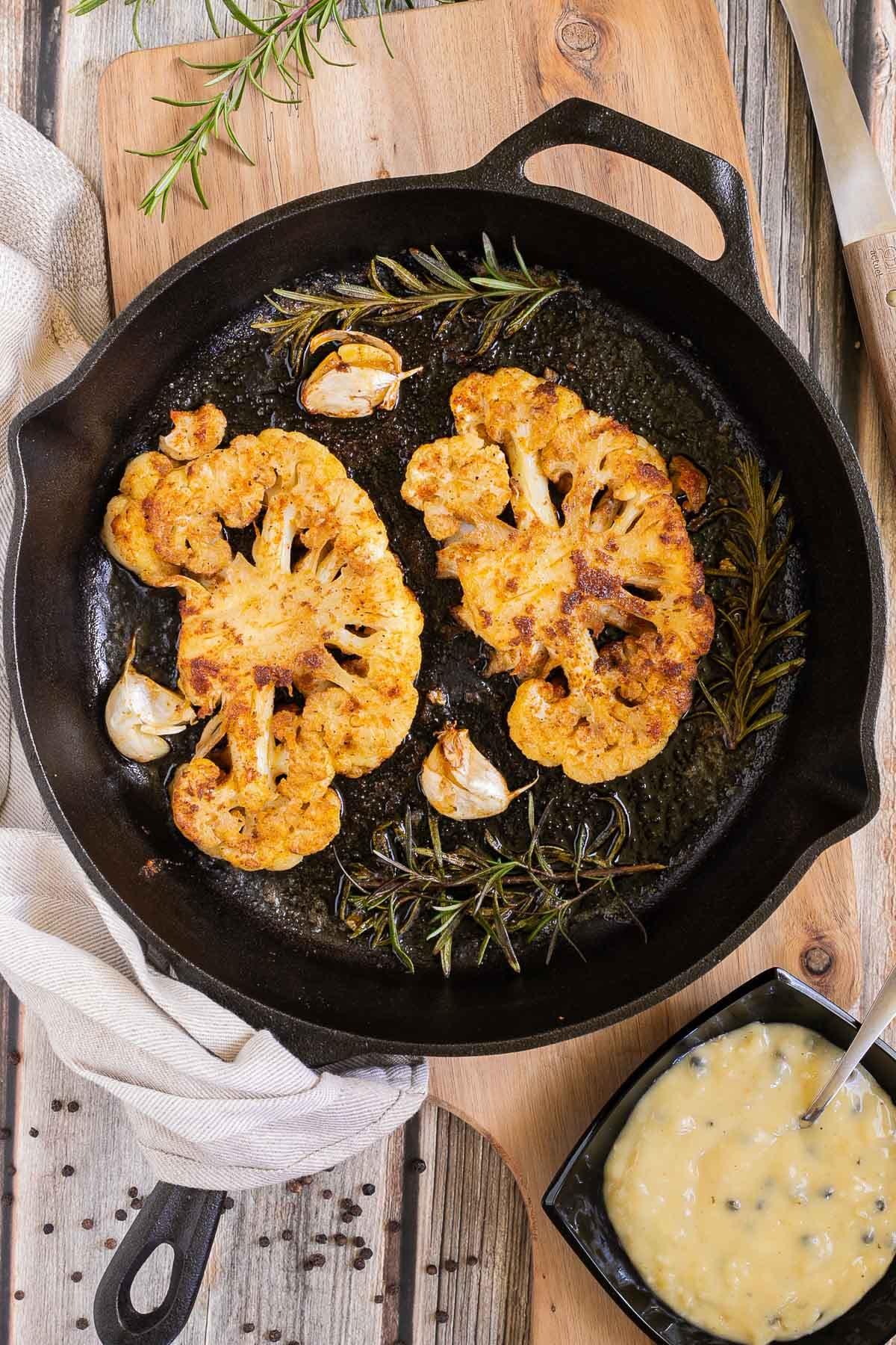 Cauliflower steaks searing in a hot pan.