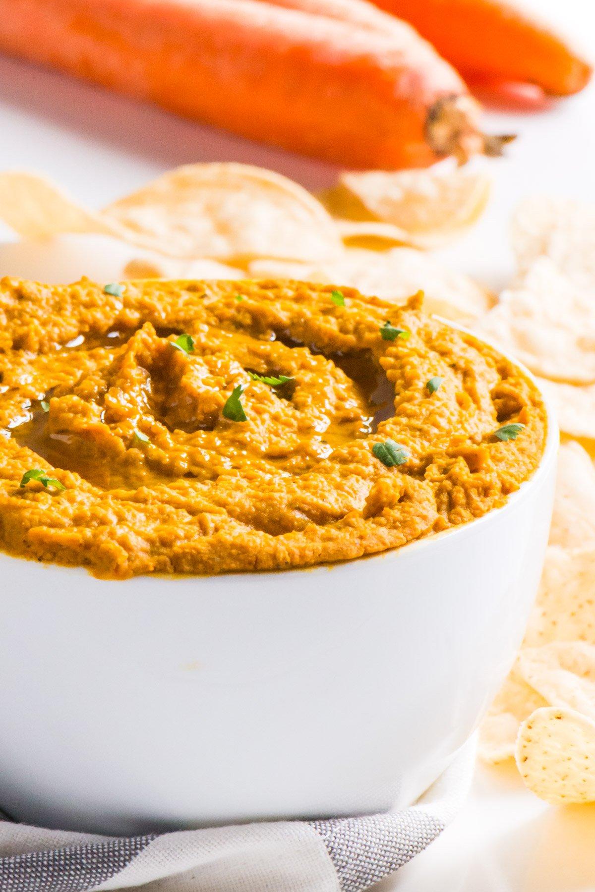 overhead shot of a carrot and ginger hummus board with various dipping options arranged artfully