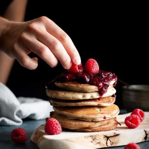 buckwheat pancakes being stacked with pulled pork and berry compote