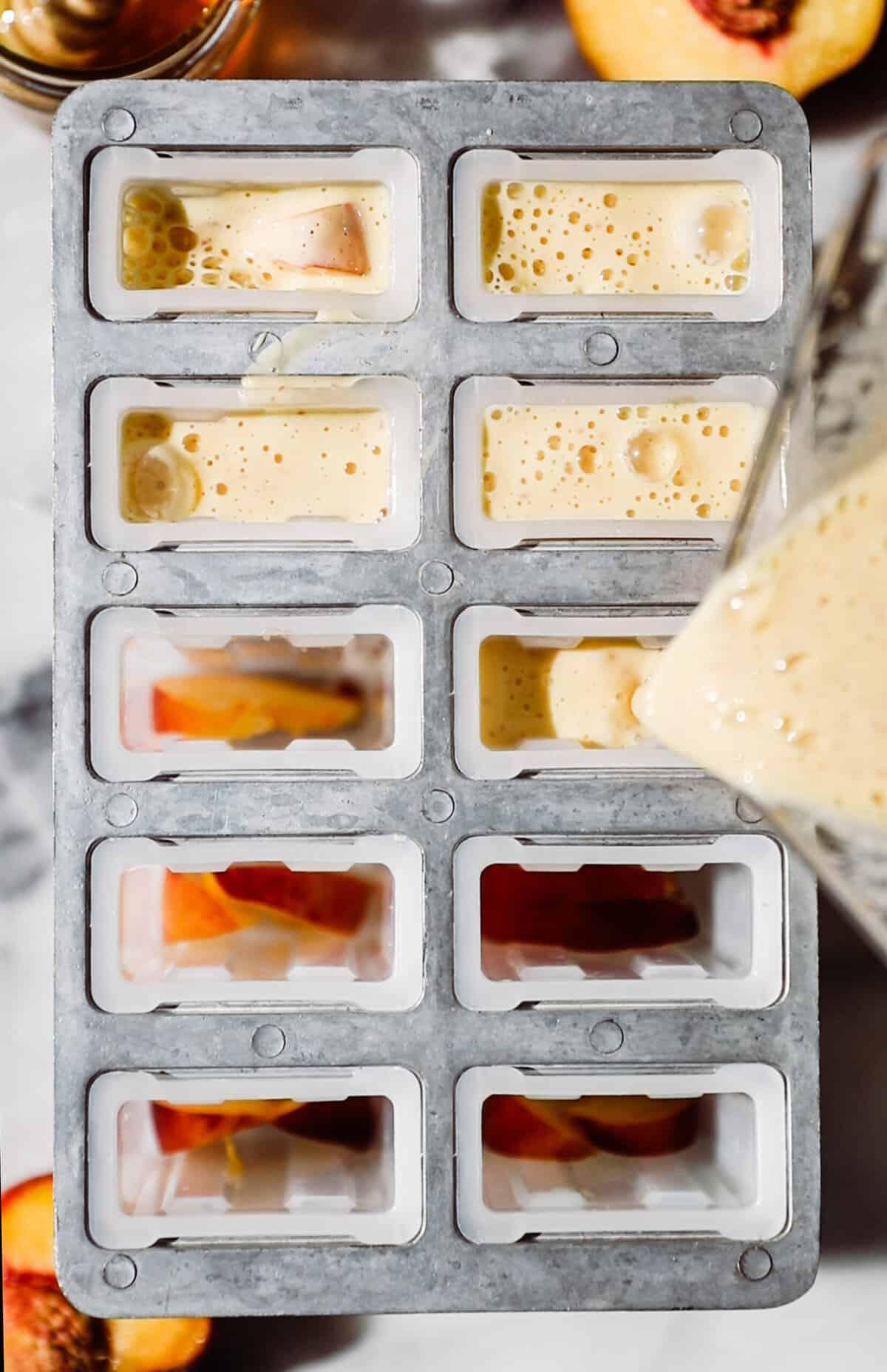 pouring peach mixture into popsicle molds