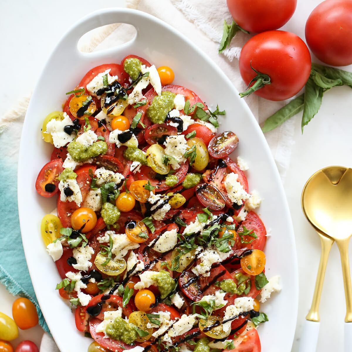 side view of a layered Caprese salad with lime dressing drizzled on top
