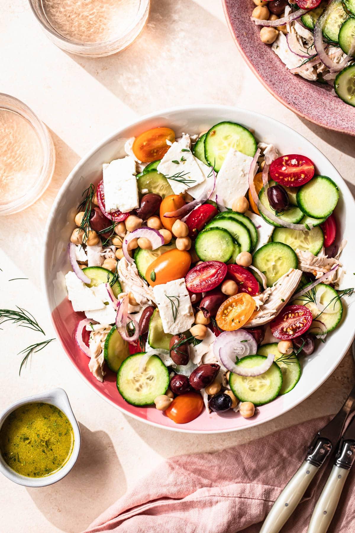 overhead view of someone assembling a lemon herb chicken and chickpea bowl