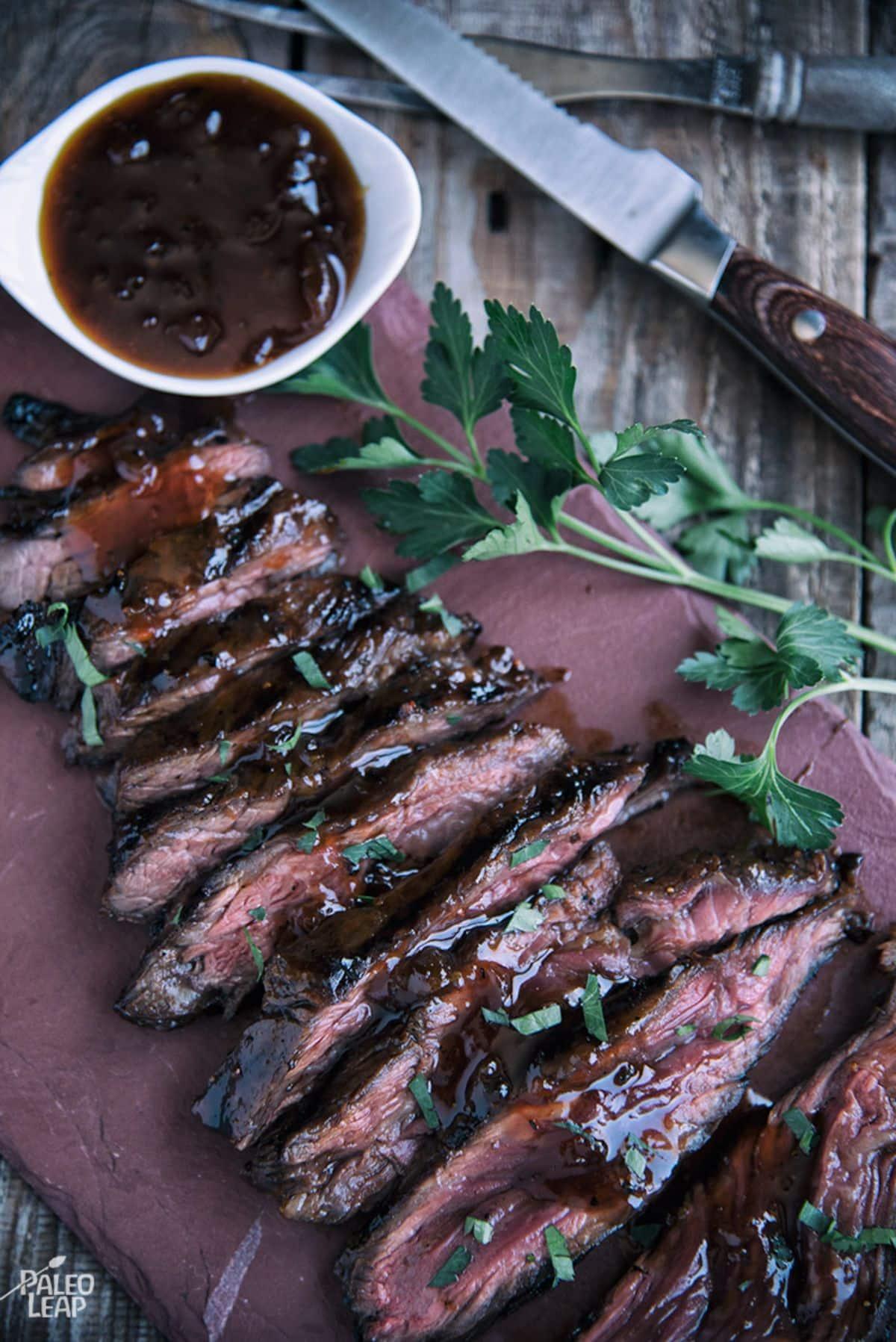 Raw flank steak marinating in apricot dijon sauce in a glass dish