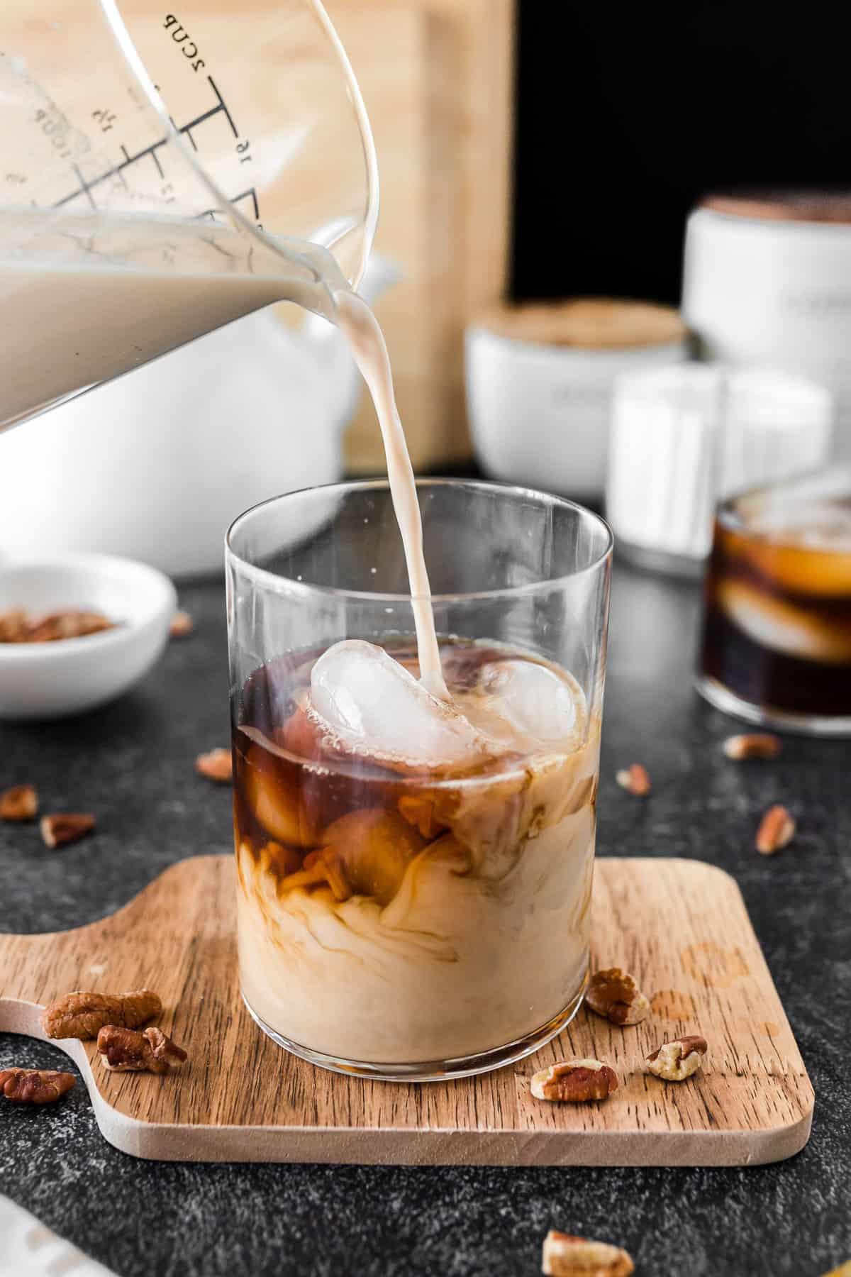 close-up shot of maple pecan lassi being poured into a glass, showing its creamy texture