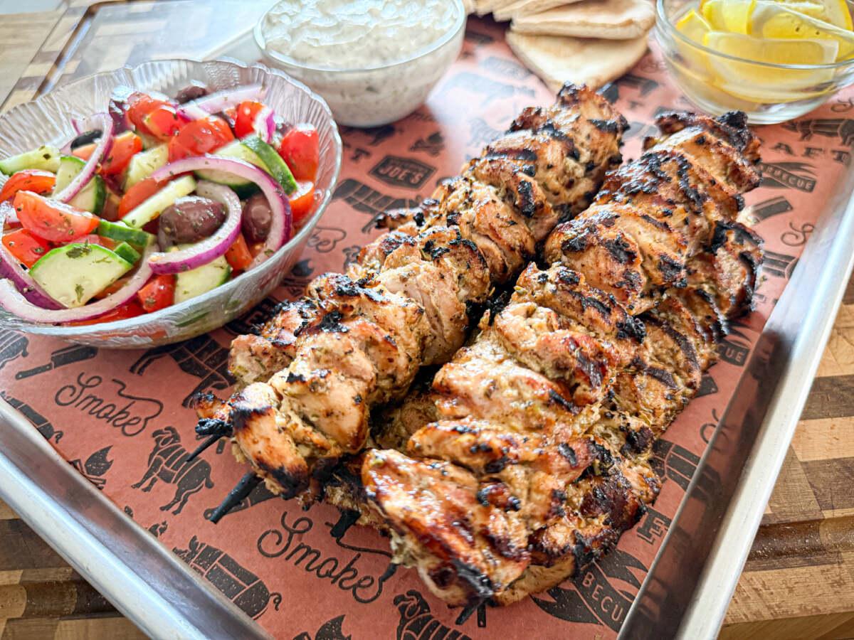 Chicken souvlaki skewers being grilled over an open flame