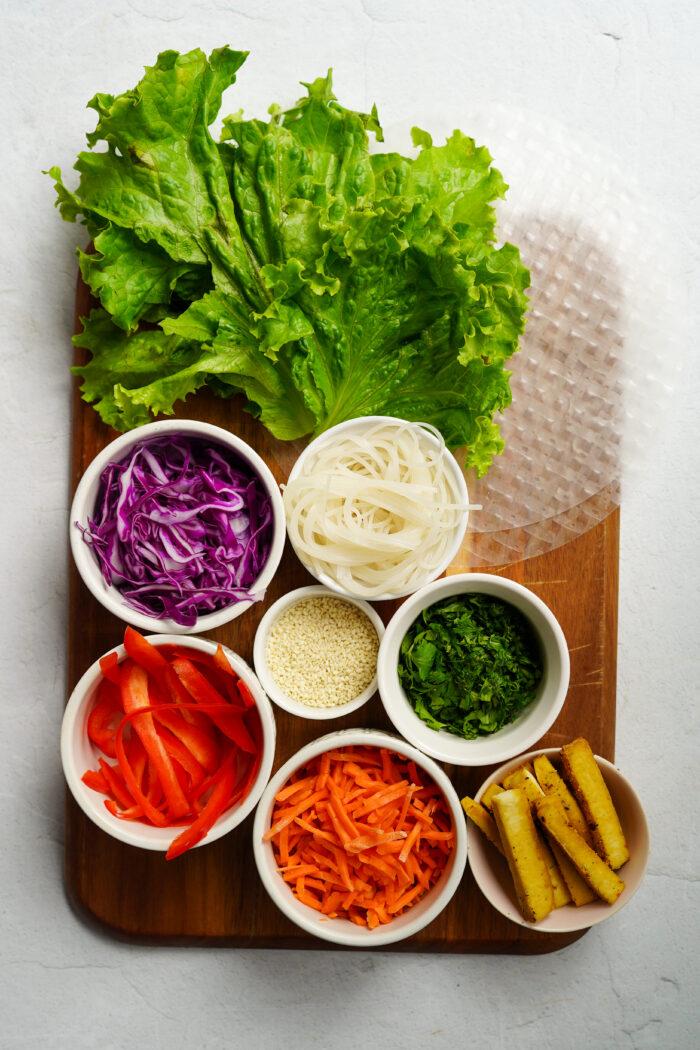 ingredients for asian slaw spring rolls laid out on a wooden table
