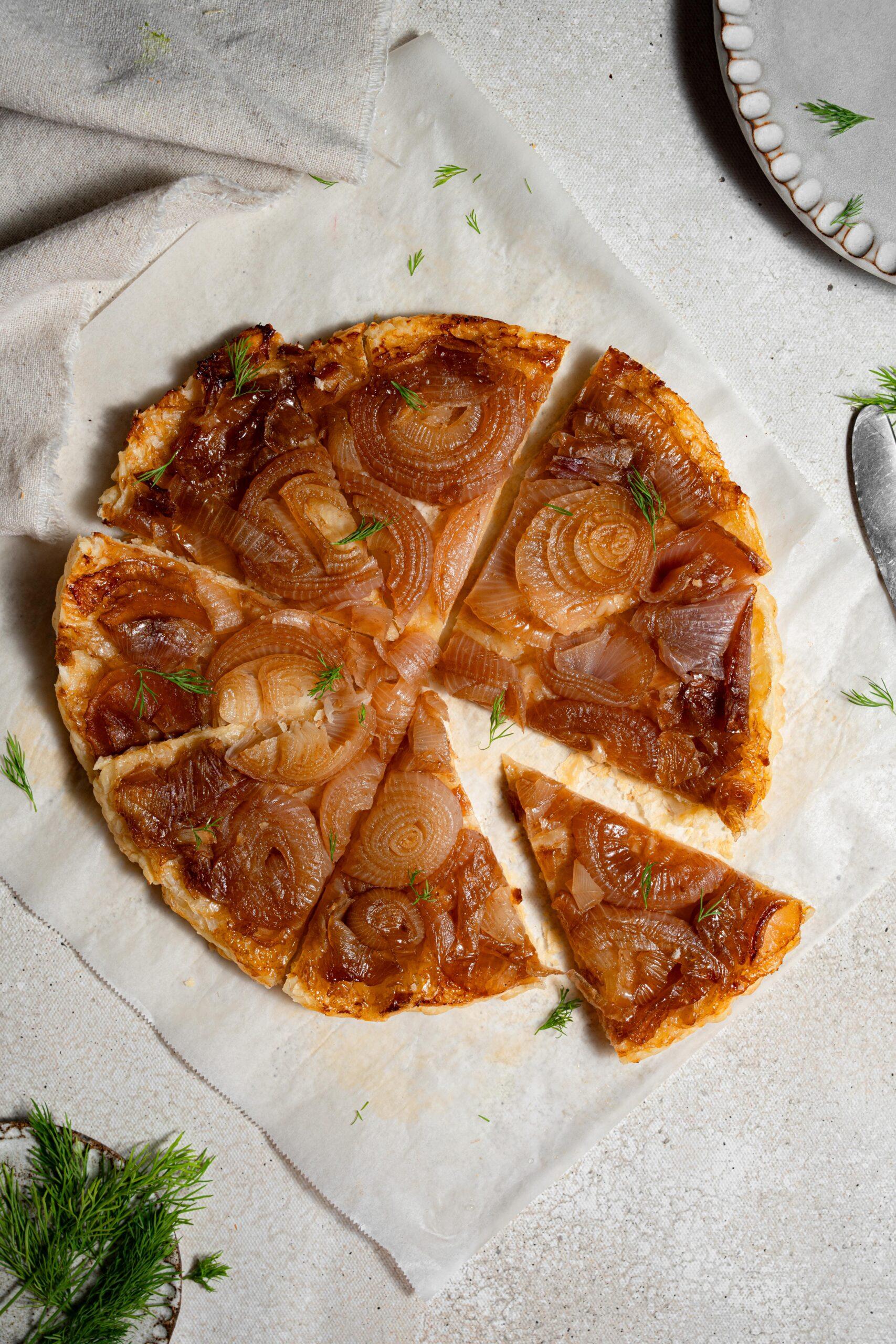 a person placing caramelized onions on a tart crust