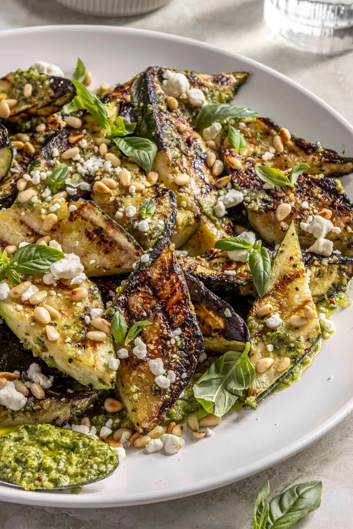 roasted zucchini slices topped with walnut pesto, garnished with fresh basil