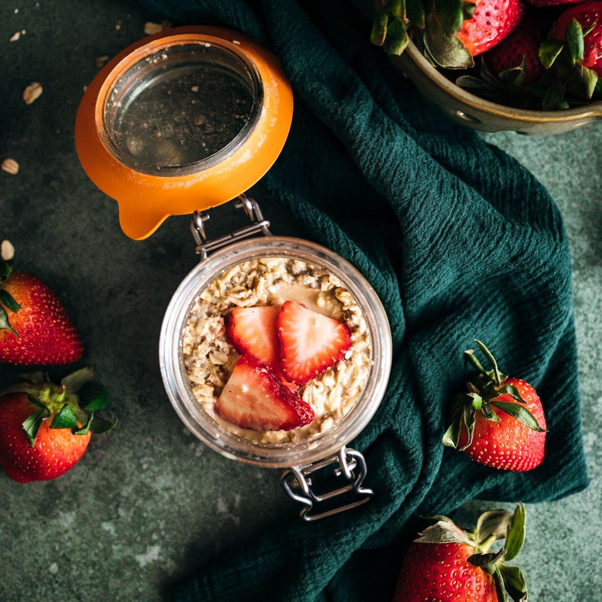 a glass of sparkling water next to a bowl of strawberry oatmeal, sunny morning setting
