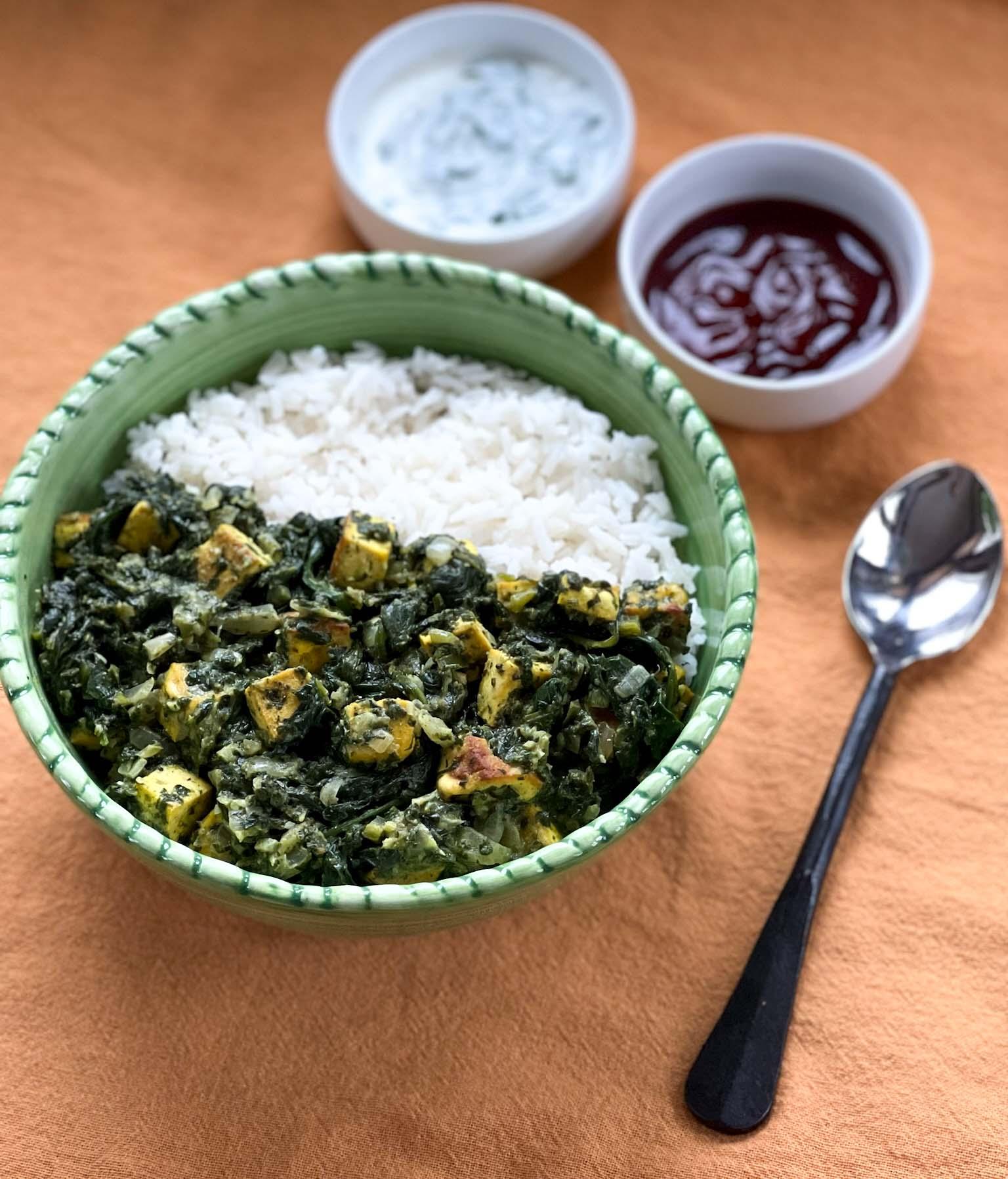 A bowl of vegan saag paneer mac on a wooden table
