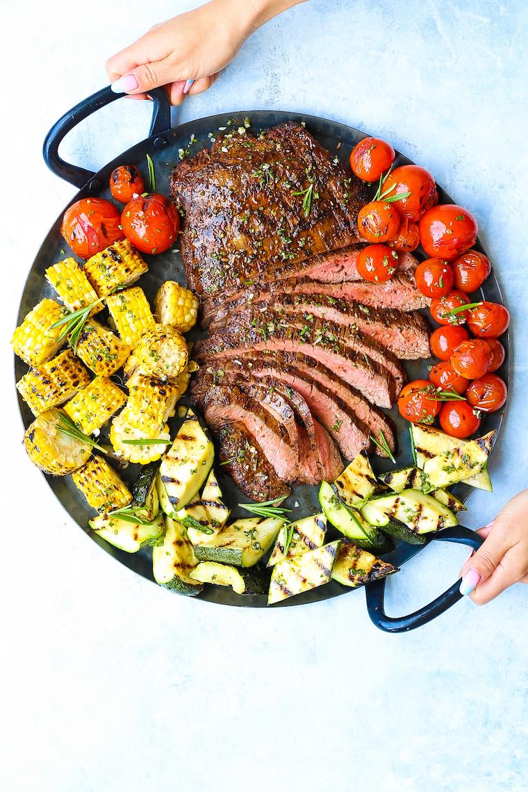 overhead shot of a grilled garlic parmesan flank steak on a platter with grilled vegetables