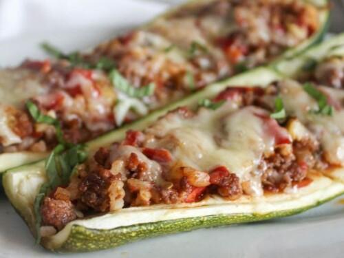 Close-up shot of uncooked zucchini boats filled with ground beef and cauliflower rice mixture