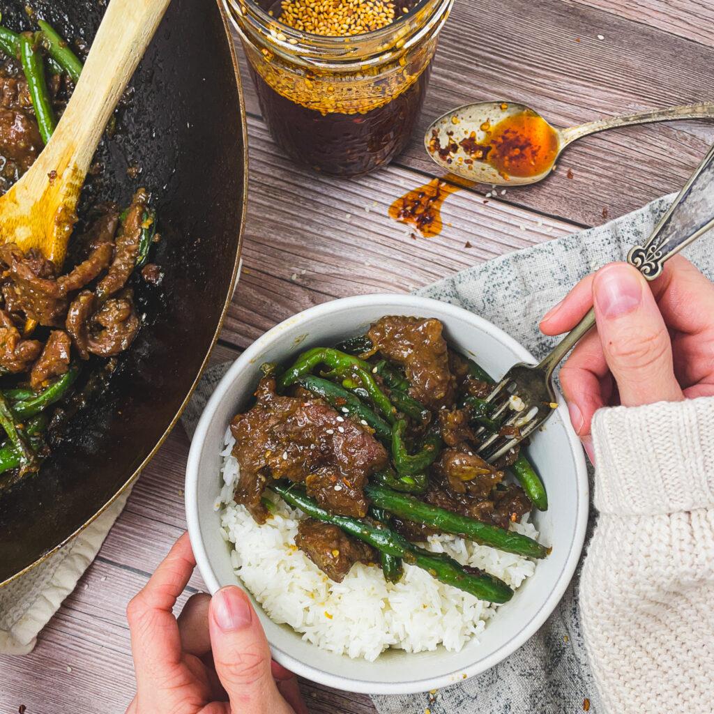 close-up of the sauce being poured over the beef and green beans