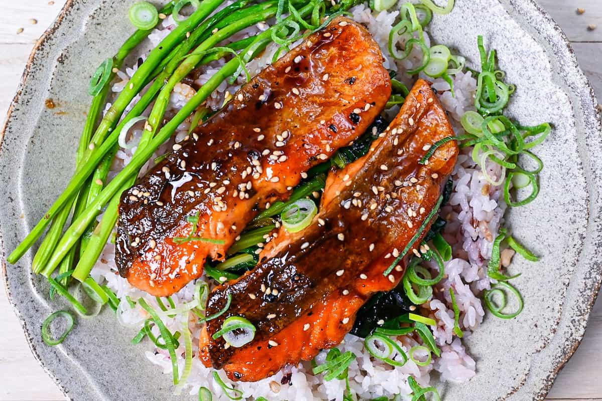 close up of teriyaki glazed salmon being brushed with sauce