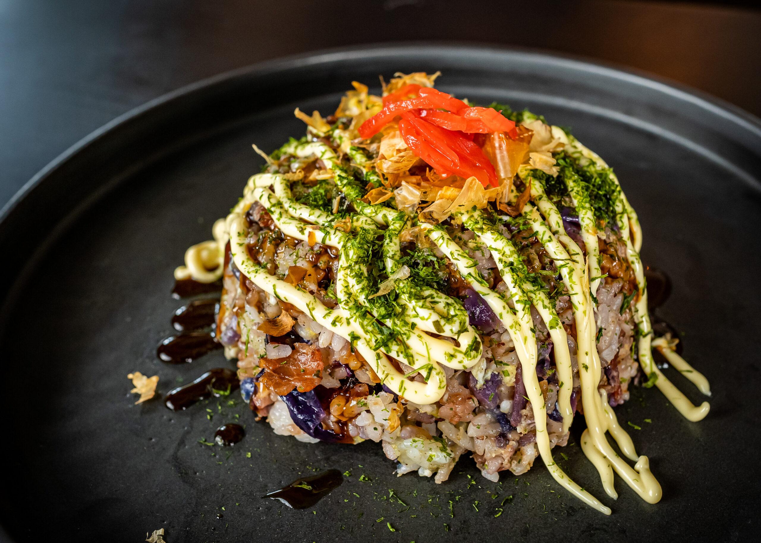 Close-up shot of okonomiyaki fried rice being stir-fried in a wok