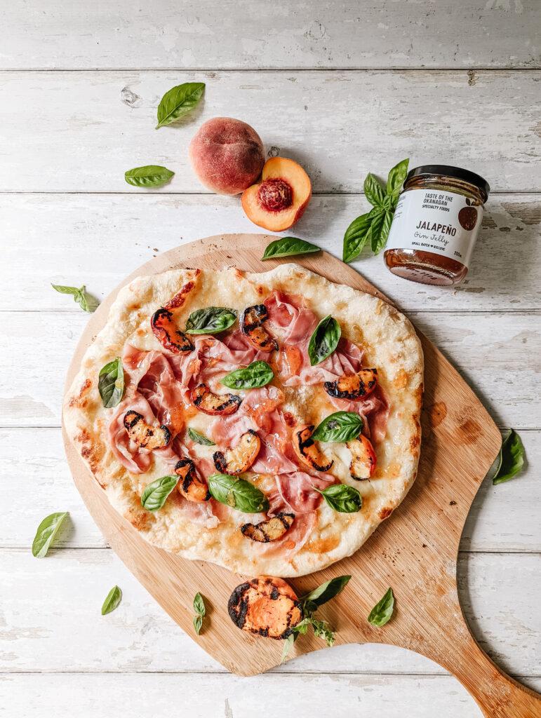 close up of grilled peach pizza with prosciutto