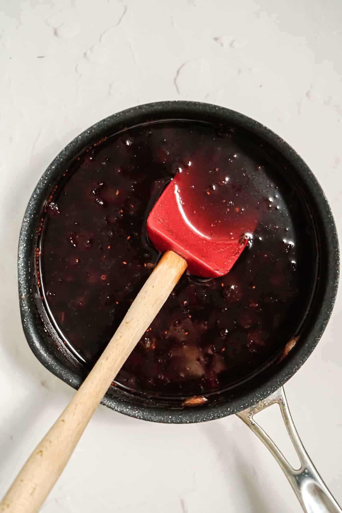 cranberry sauce being stirred in a saucepan
