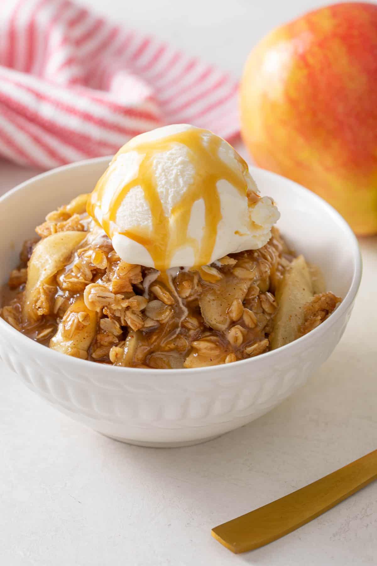 sliced irish cream apple crisp with a scoop of vanilla ice cream and caramel drizzle