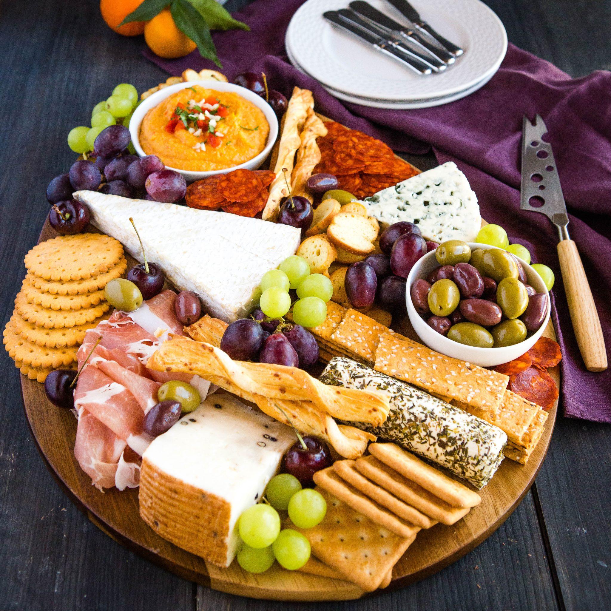 various cheeses, crackers, and grapes on a charcuterie board