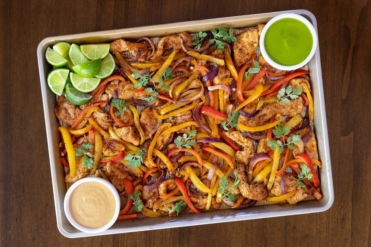 overhead shot of cooked sheet pan fajitas being served in warm tortillas