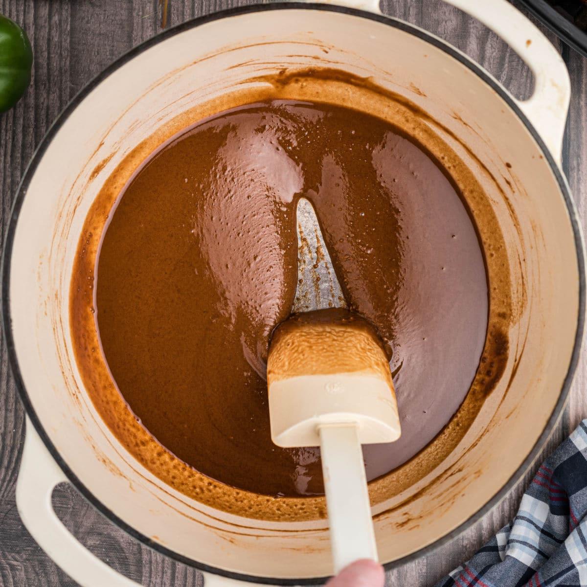 Close up of a dark roux being stirred in a pot