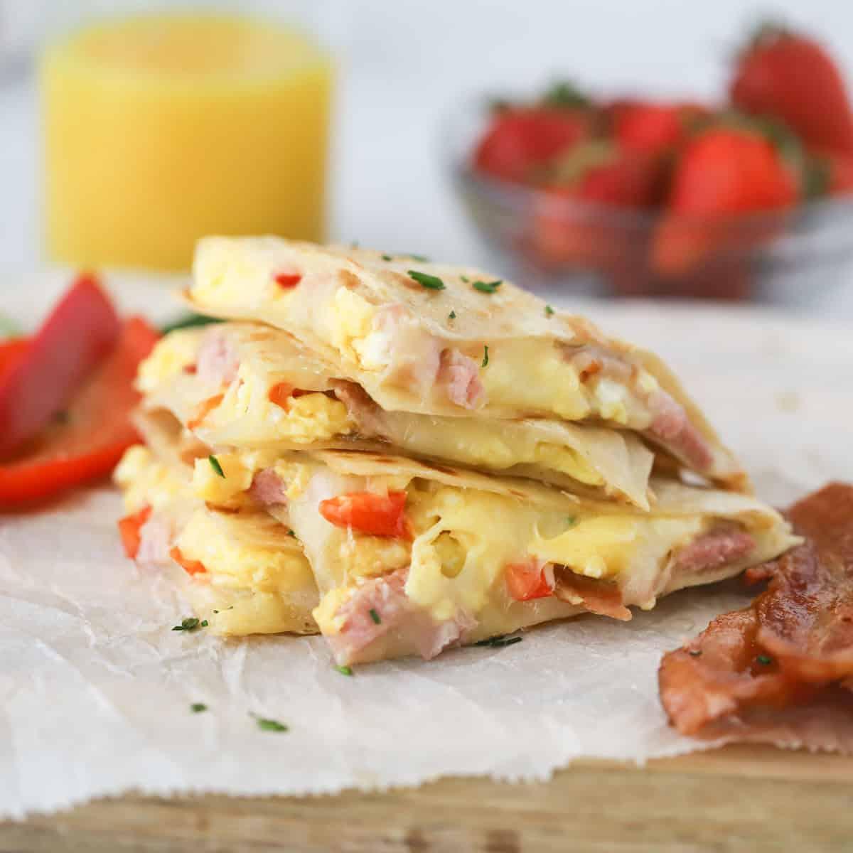 A person cutting a breakfast quesadilla in half, with cheese oozing out