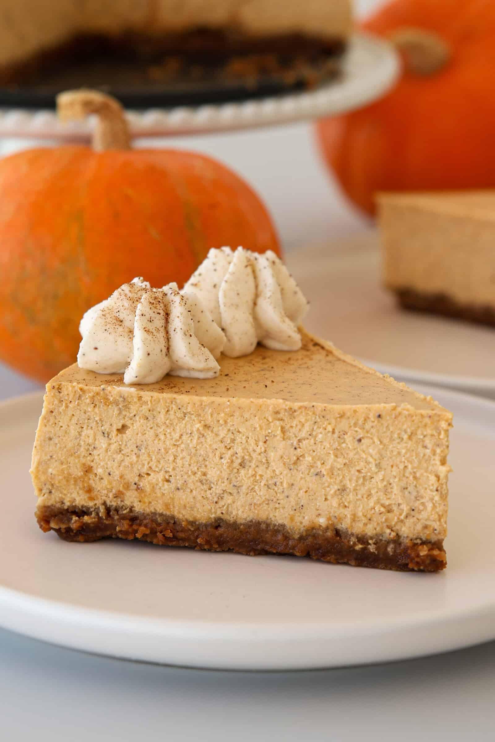 slice of pumpkin spice cheesecake with whipped cream and a sprinkle of cinnamon