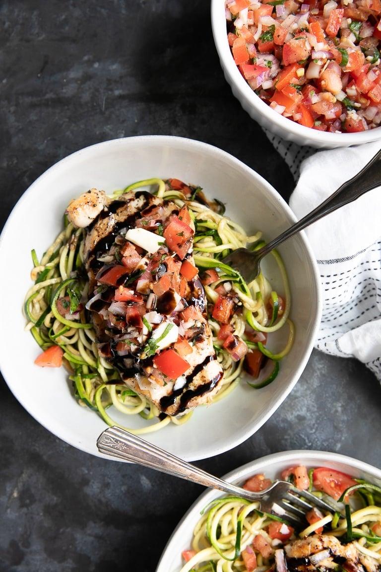 chef drizzling balsamic glaze over zoodle stir-fry