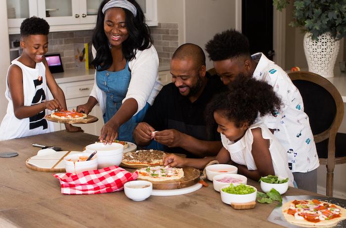 family making pizza together in kitchen
