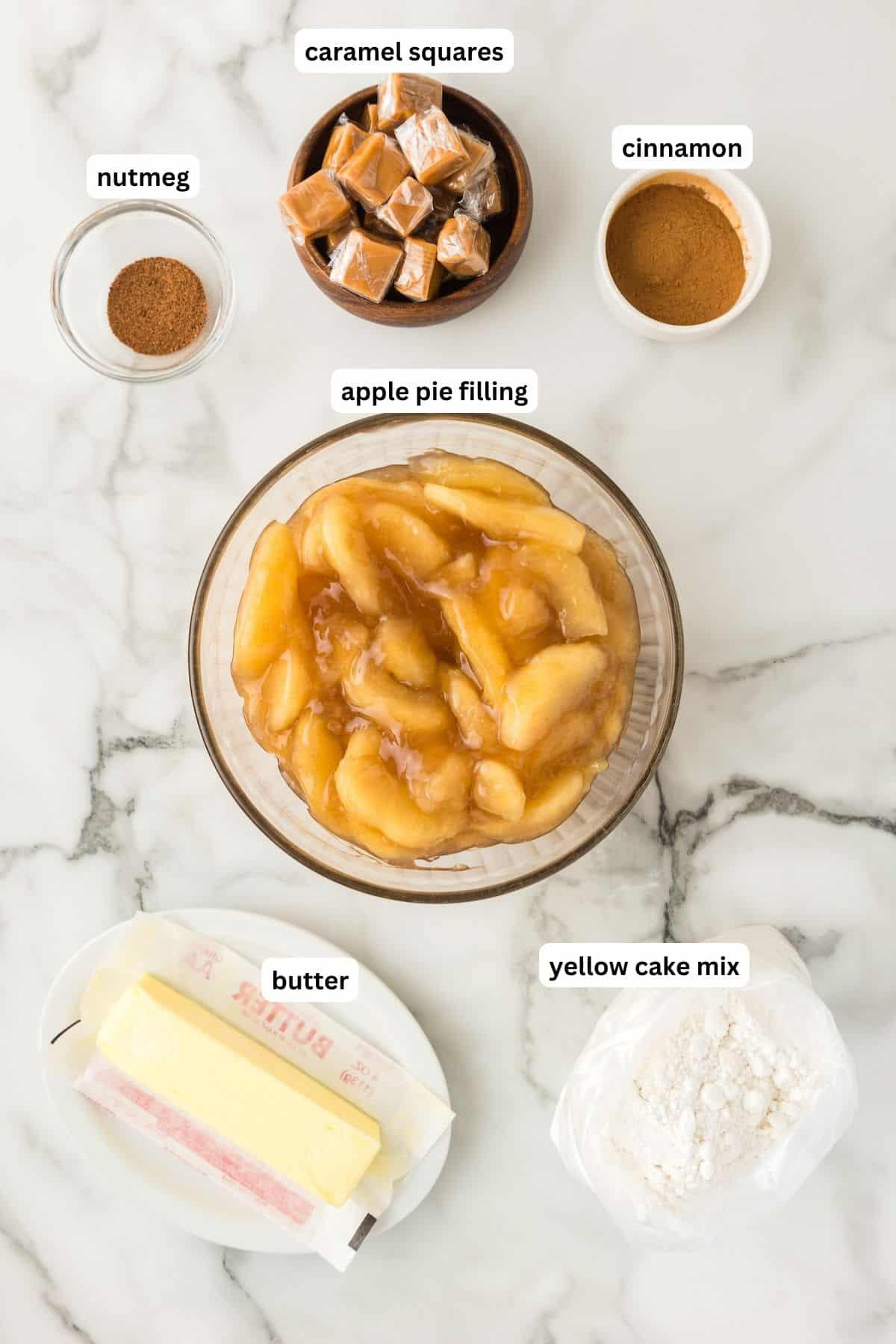 Ingredients laid out for caramel apple dump cake, including apples, cake mix, caramel sauce, and butter