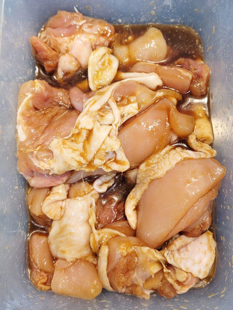 raw chicken thighs marinating in a bowl with sake mirin marinade