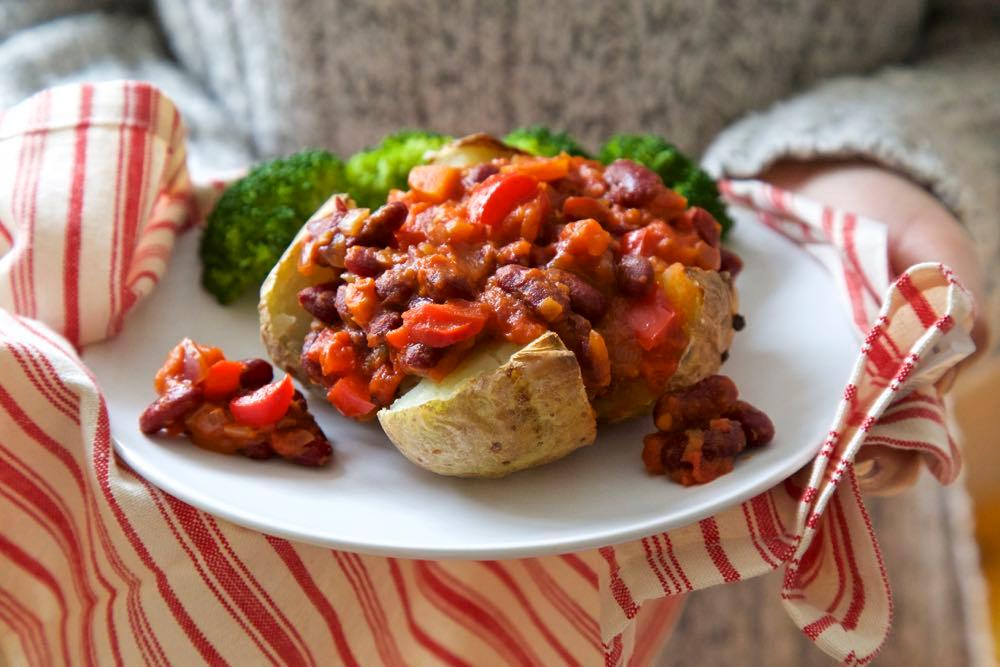 a spread of vegan chili baked potatoes with various toppings