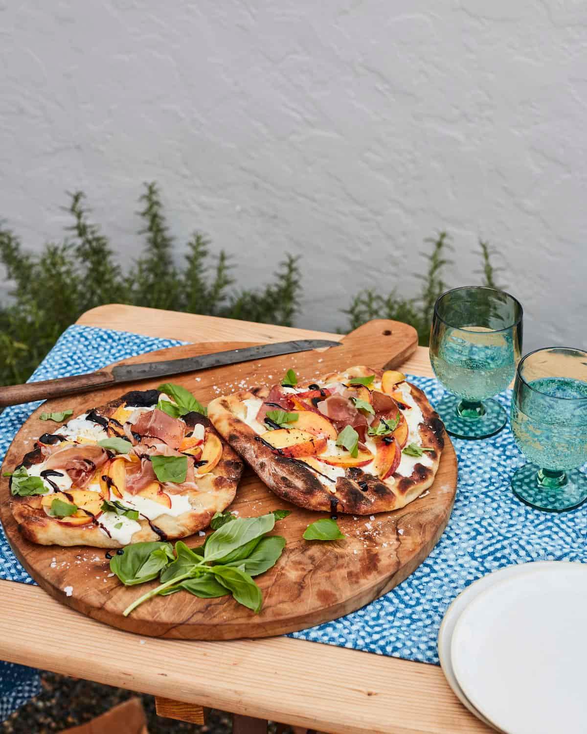 slices of grilled peach pizza on a wooden board