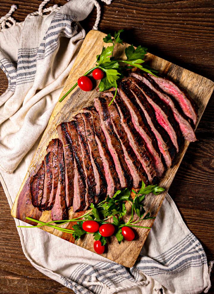 grilled flank steak being sliced on a cutting board
