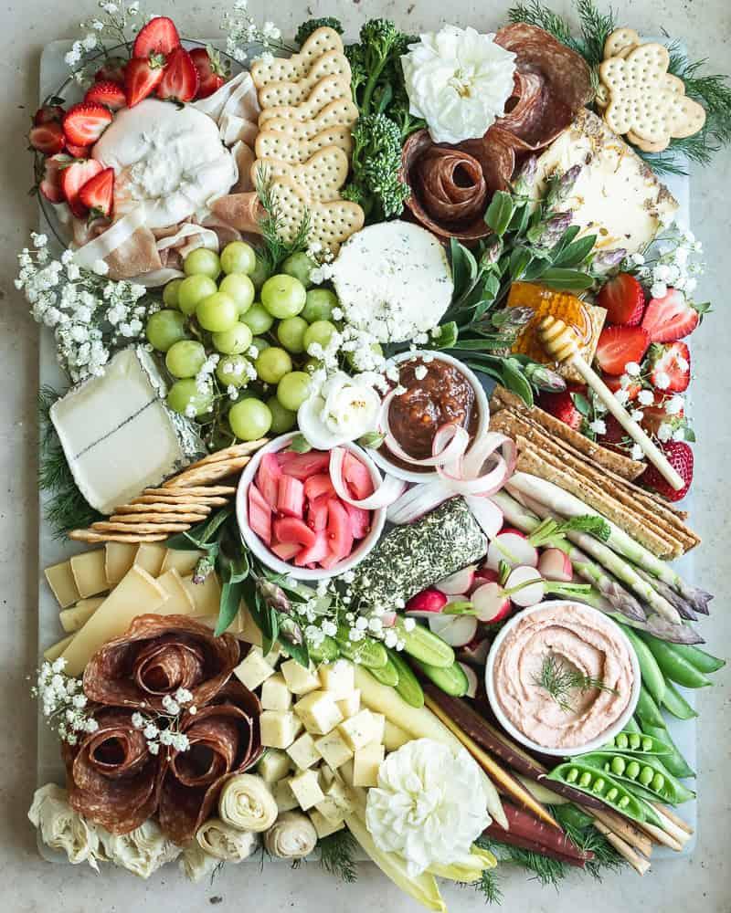 close up of different cheeses on a cheese board with spring flowers in the background