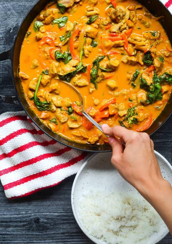a spoon scooping up yellow chicken curry with coconut milk