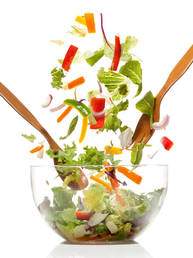 salad being tossed in a bowl