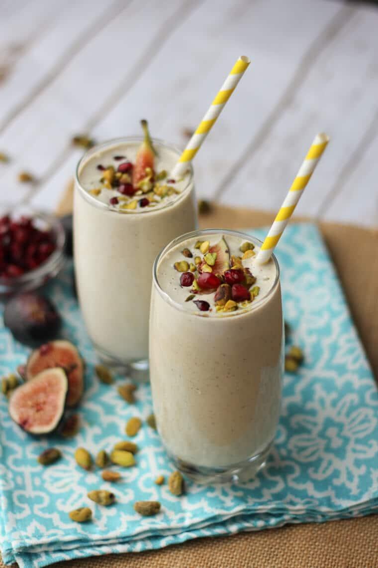 a close up of a pomegranate and pistachio milkshake being poured into a glass