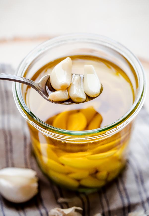 Close-up of garlic cloves simmering in olive oil in a saucepan