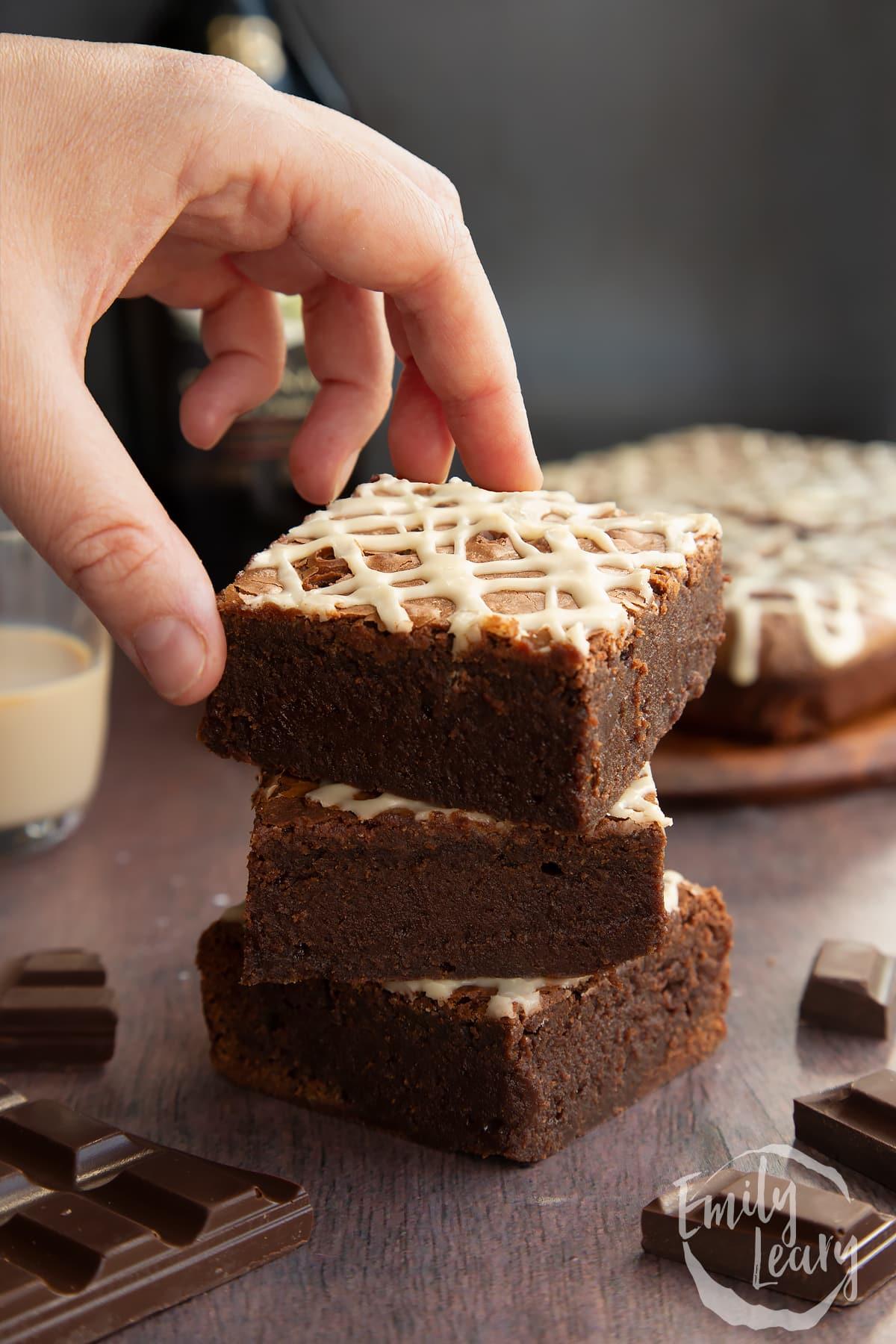 A person taking a bite out of a Baileys brownie, with a satisfied expression.