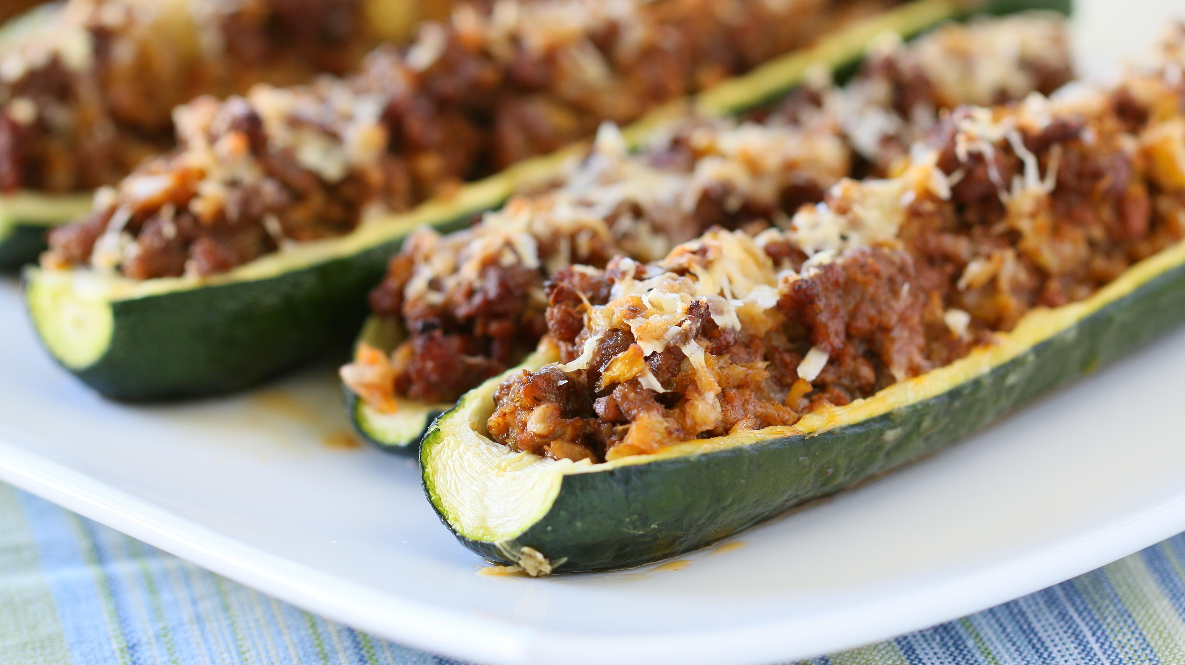 Ground beef and cauliflower rice stuffed zucchini boats on a rustic wooden table