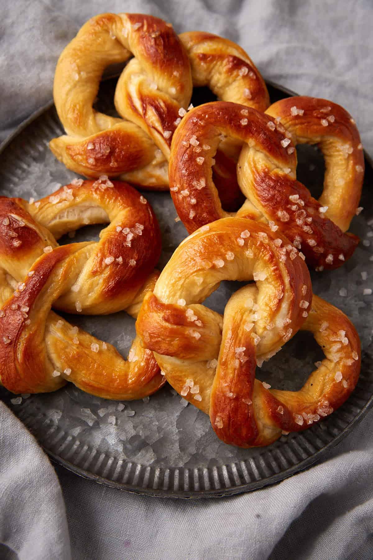 freshly baked buttery soft salt dough pretzels on parchment paper, close up with coarse salt