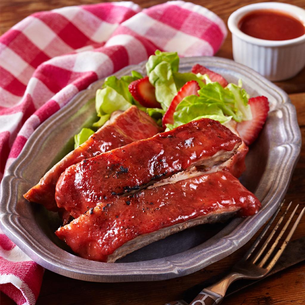 Family enjoying strawberry glazed ribs at an outdoor barbeque.